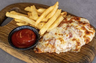 Kids chicken parmigiana with fries and tomato sauce on a board